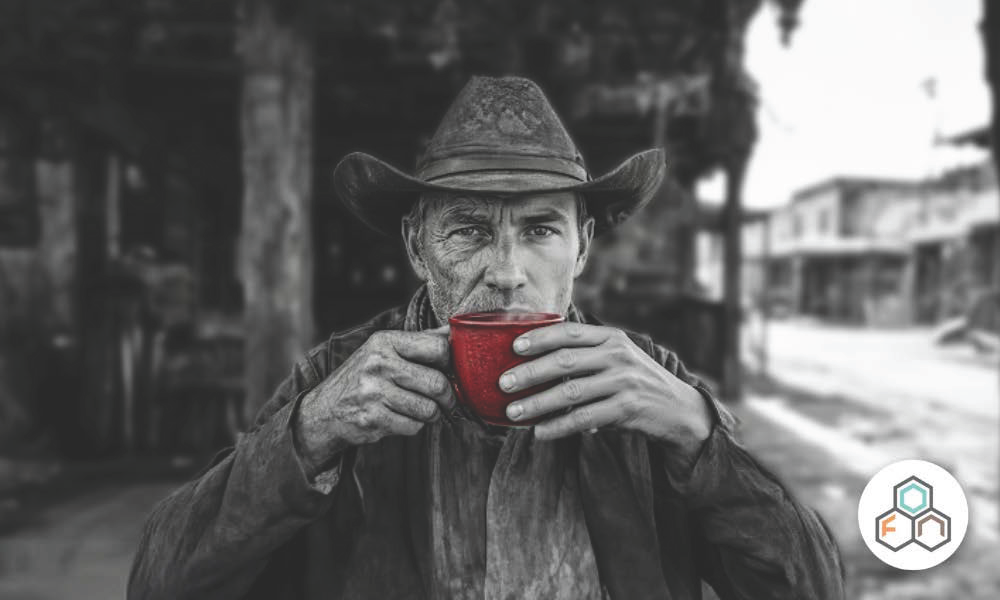 biohacking for longevity; Black-and-white portrait of a man wearing a cowboy hat and holding a bright red coffee mug to his lips. The left side of his face and his left hand are aged, while the right side of his face and his right hand are young. The background shows a blurred old western-style street.
